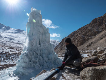 Man on snowcapped mountain against sky during winter