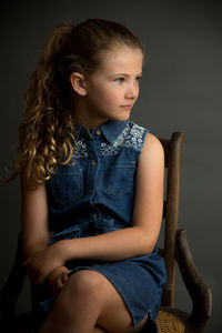 Portrait of girl sitting against gray background