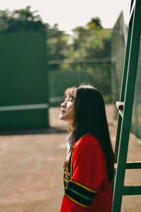 Beautiful woman with eyes closed standing by ladder