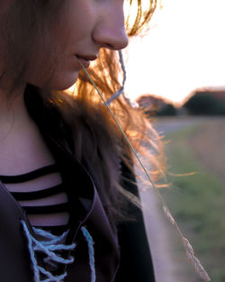 Close-up of young woman carrying plant in mouth