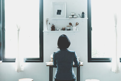 Rear view of woman sitting at home