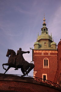 Low angle view of statue by wawel cathedral against sky during sunset