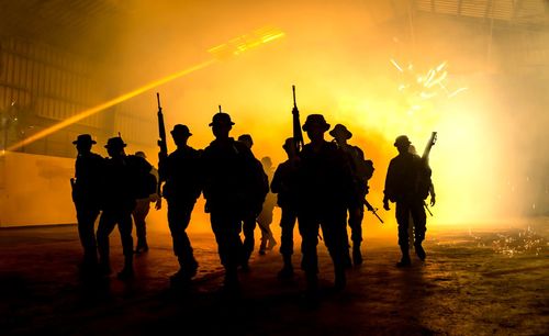 Silhouette soldiers walking on field at night