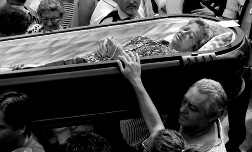 Crowd carrying woman in coffin during fiesta de santa marta de ribarteme