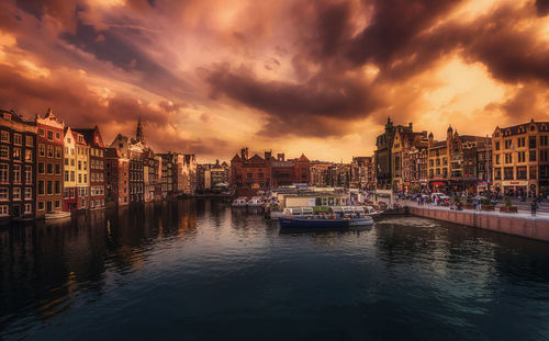 Canal amidst buildings against sky during sunset