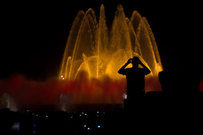 Silhouette man standing against fountain at night