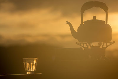 Close-up of illuminated lamp on table against sunset sky