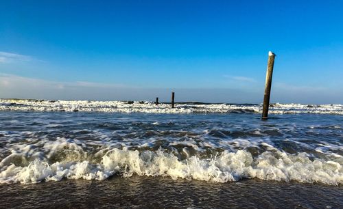 Waves rushing towards shore against blue sky