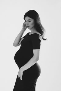 Side view of young woman standing against white background