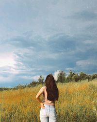 Rear view of woman standing on field against sky