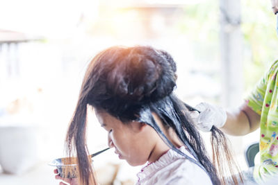 Hairdresser applies a hair mask to the woman in the beauty salon. 