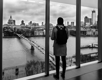 Rear view of man standing by buildings against sky