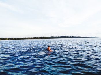 Rear view of man in sea against sky