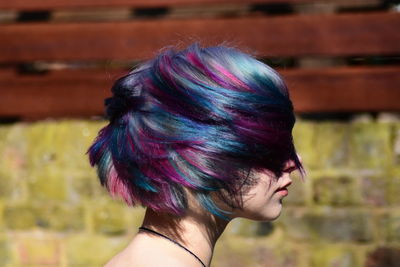 Hipster woman tossing colorful dyed hair outdoors