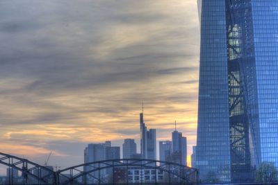 Low angle view of modern buildings against cloudy sky