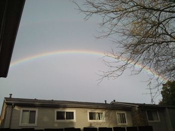 Low angle view of rainbow over building against sky
