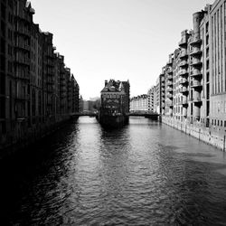 Canal amidst buildings against clear sky