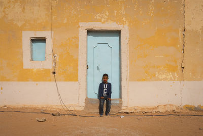 Full length of man standing against door of building