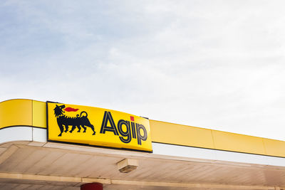 Low angle view of yellow sign against sky