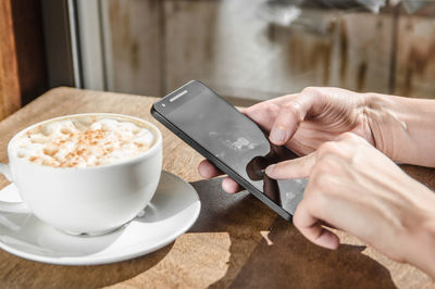 Close-up of woman holding coffee cup on table
