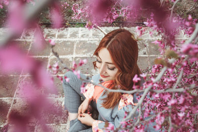 Woman sitting on footpath seen through blooming flowers