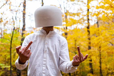 Man wearing bowl on head gesturing against trees