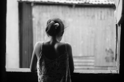 Side view of woman looking through window