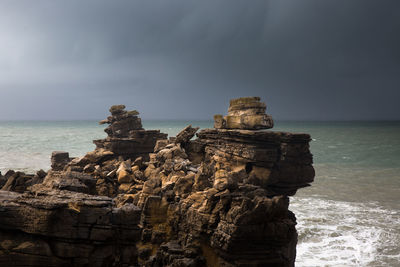 Rock formation on beach against sky