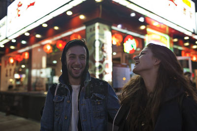 Portrait of smiling young woman standing in city at night