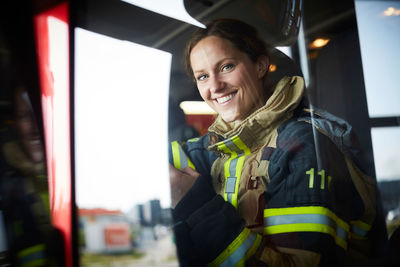 Portrait of smiling female firefighter sitting in fire engine