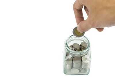 Close-up of hand holding jar against white background