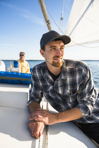 Man sitting on boat in sea against sky