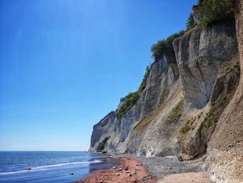 Rock formations on beach against clear blue sky