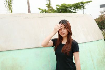 Young woman standing against wall