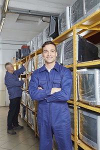Worker standing with arms crossed in monitor storage of computer recycling plant