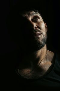 Close-up of sad man looking away against black background