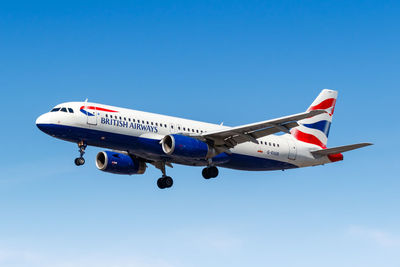 Low angle view of airplane flying against clear blue sky