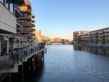 River amidst buildings in city against clear sky