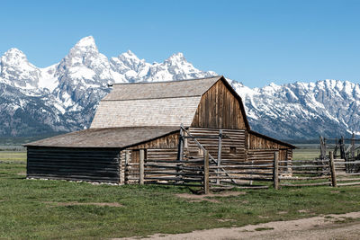Barn on field against snowcapped mountains