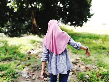 Rear view of girl wearing hijab walking on field