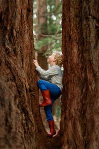 Full length of woman on tree trunk in forest