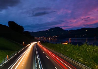 Light trails on road against sky at night