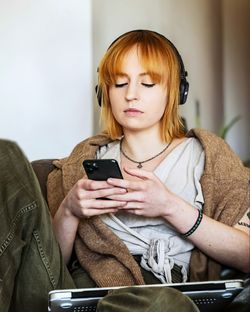 Young woman using phone while sitting at home