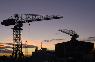 Low angle view of crane at construction site during sunset