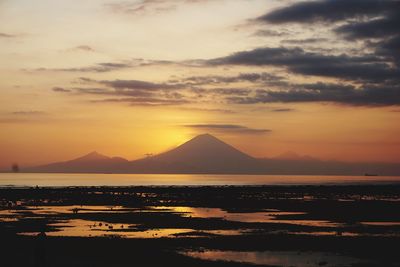 Scenic view of sea against dramatic sky during sunset