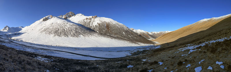 Panoramic view of snowcapped mountains against clear blue sky