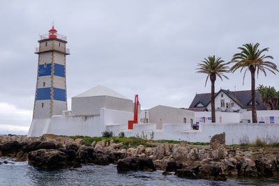 Lighthouse by sea against sky