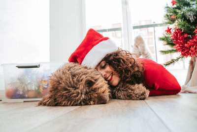 Woman lying down on floor at home with her dog. christmas time 