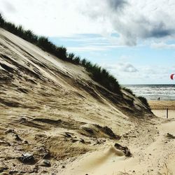 Scenic view of beach against cloudy sky