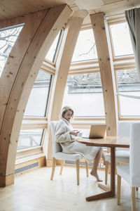 Woman using mobile phone while sitting on chair at home